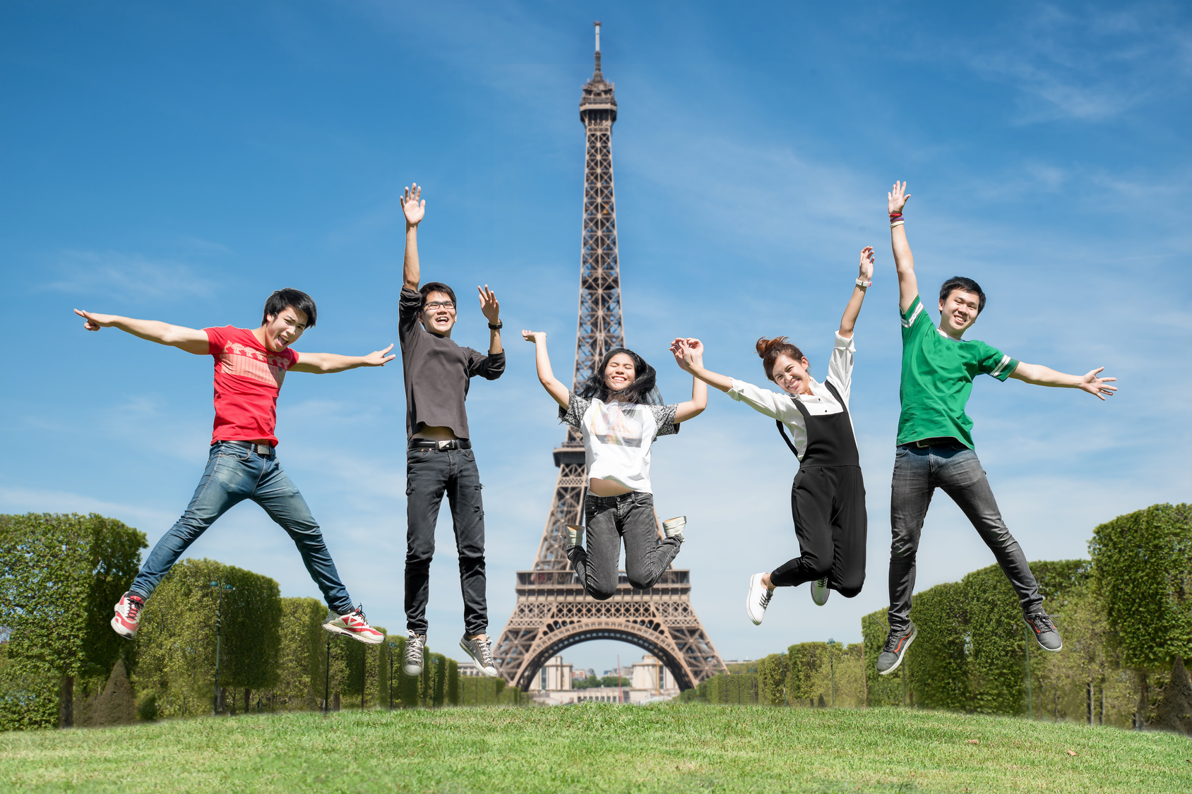 summer, holidays, vacation, happy people concept - group of friends jumping on the park near Eiffle tower in Paris, France